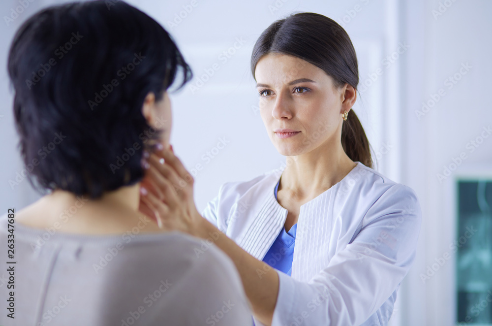 A serious female doctor examining a patient's lymph nodes A serious female doctor examining a patient's lymph nodes