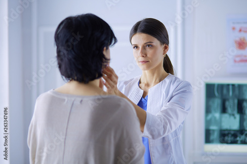 A serious female doctor examining a patient s lymph nodes