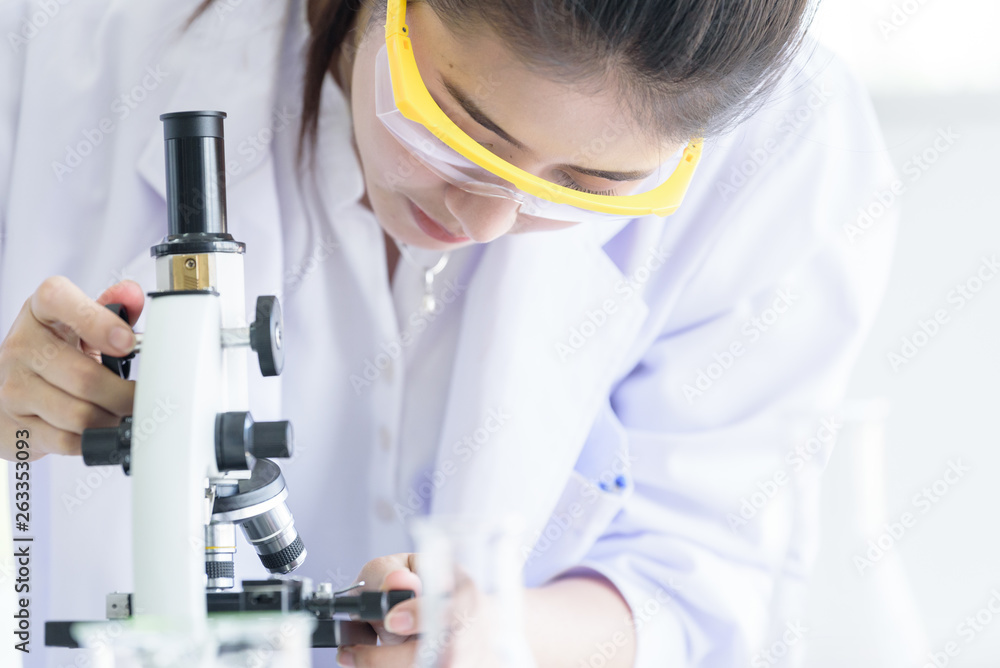 Asian young student scientist researching with a microscope in a laboratory. Asian young student scientist researching with a microscope in a laboratory.