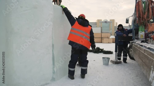 Slinger in a vest and orange helmet joins the ice block