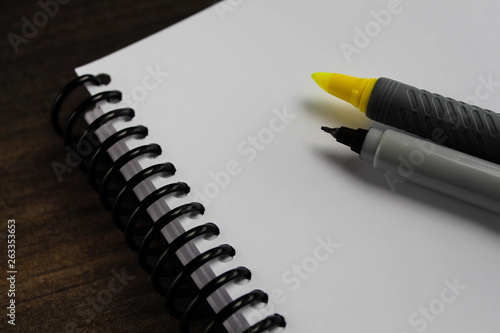 Spiral notepad paper with highlighter and pen on the wooden background photo