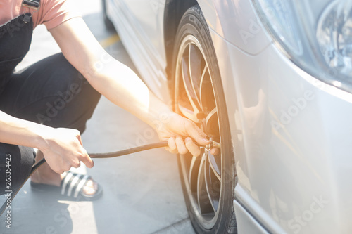 Wallpaper Mural Asian woman filling air into a car tire to increase pressure car tire Torontodigital.ca