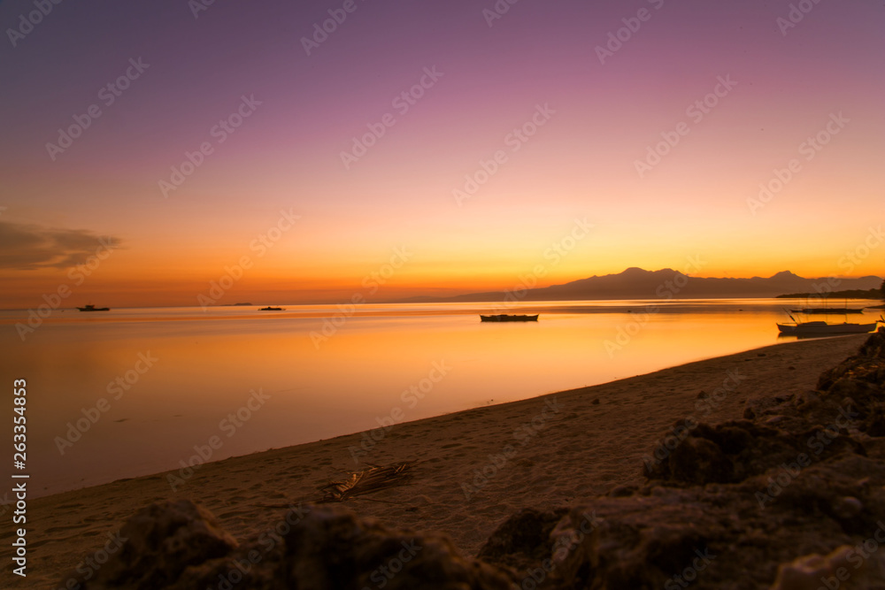 outrigger fisher boat at the sea shore in a long expose photography and a white sand tropical beach, a tranquil summer sunset dusk background scene