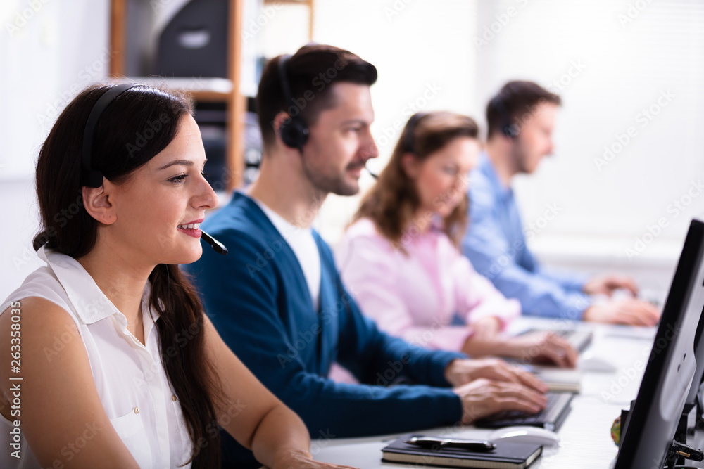 Smiling Customer Service Executives Using Earphones Smiling Customer Service Executives Using Earphones