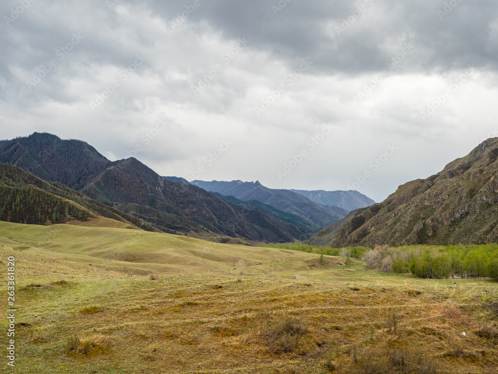 Dramatic clouds in the sky over the steppe and mountain peaks in the Altai, Russia