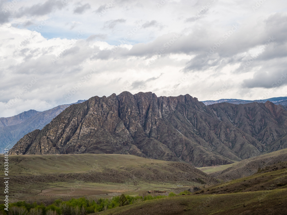 Dramatic clouds in the sky over the steppe and mountain peaks in the Altai, Russia