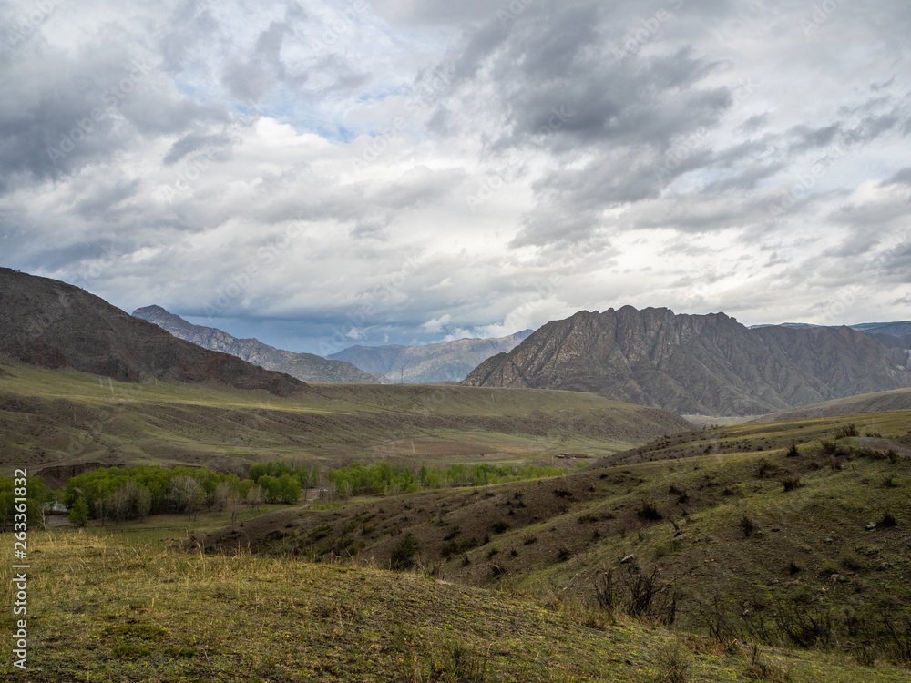 Dramatic clouds in the sky over the steppe and mountain peaks in the Altai, Russia