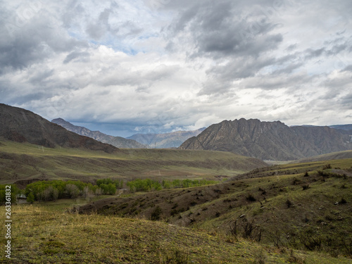 Dramatic clouds in the sky over the steppe and mountain peaks in the Altai, Russia