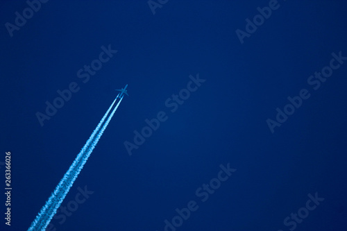  long-haul airplane in the evening sky with contrail