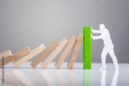 Foto Human Figure Stopping Wooden Dominos Blocks