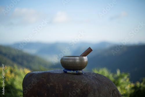 Tibetan singing bowl with sanskrit engraving pattern and sticks on the rock. .(The Nepal word on the tibetan singing bowls means wish everything is fine.) photo
