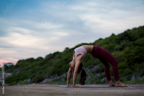 Side view of healthy happy women practicing yoga. woman in Urdhva Dhanurasana yoga asana in upward bow pos, beautiful landscape view sky on evening nature evening outdoor.