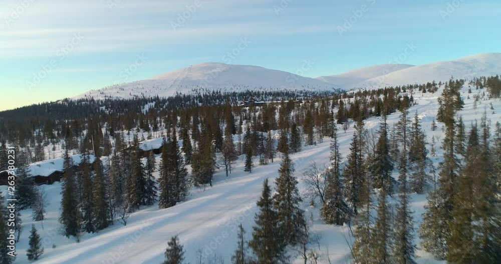 Pallas, aerial, rising, drone shot, over spruce forest and buildings, revealing a hotel and Ounastunturit fells, in Pallas-yllastunturi national park, winter evening, in Muonio, Lapland, Finland Pallas, aerial, rising, drone shot, over spruce forest and buildings, revealing a hotel and Ounastunturit fells, in Pallas-yllastunturi national park, winter evening, in Muonio, Lapland, Finland