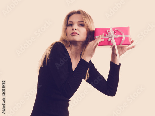 Girl holding present shaking pink gift box