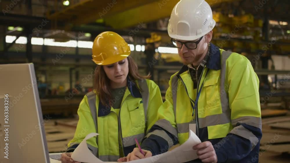 Two young engineers in helmets and uniform Two young engineers in helmets and uniform