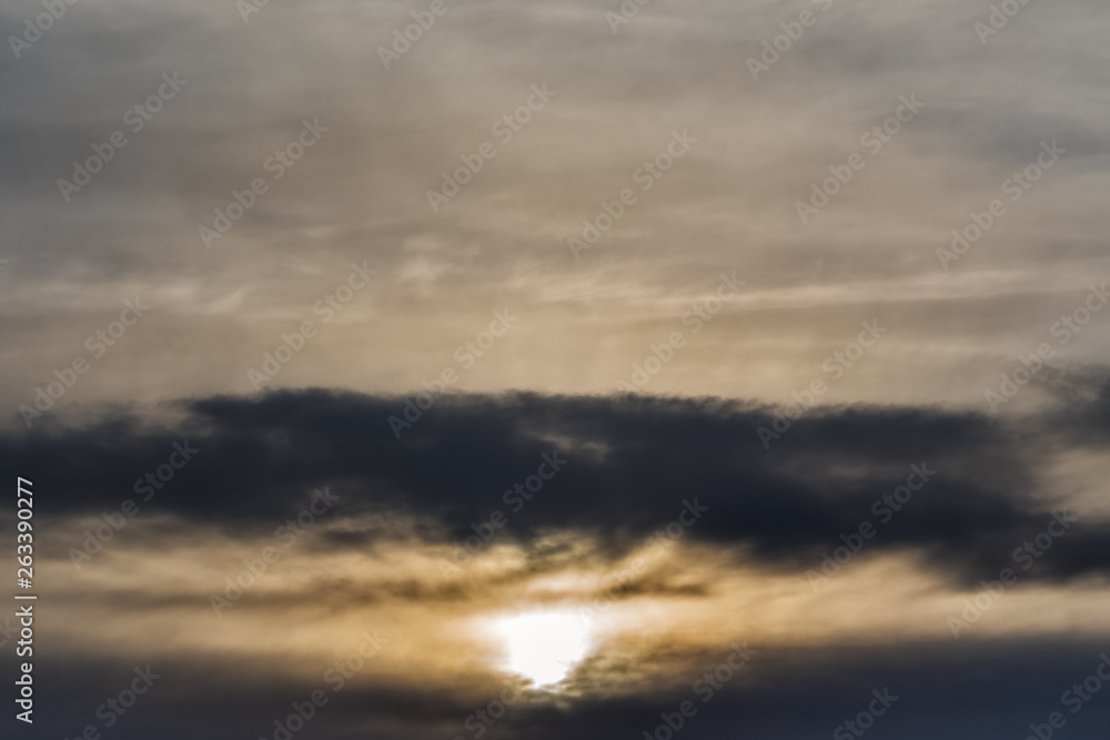 The setting sun against the blurred cloudy sky