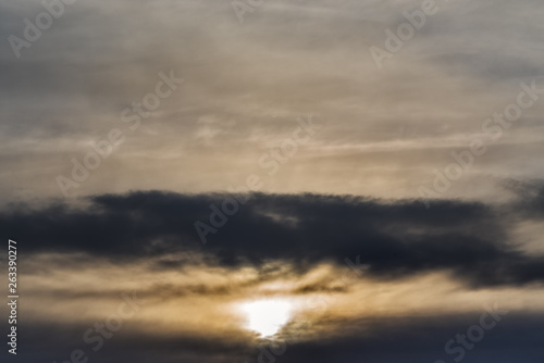 The setting sun against the blurred cloudy sky