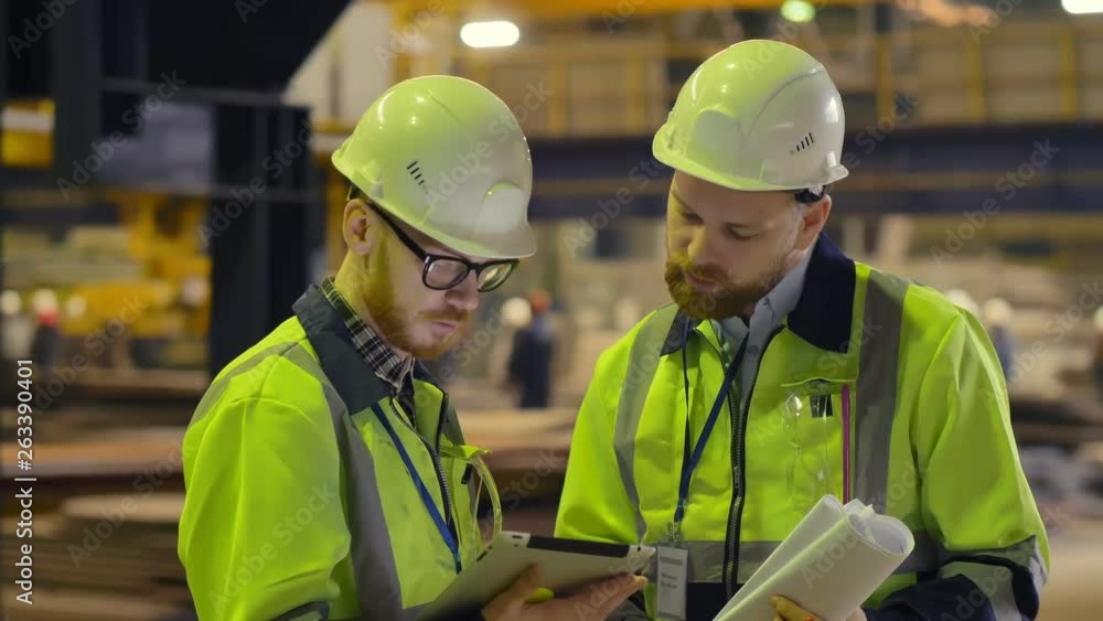 Factory workers in a hard hat using a tablet computer Factory workers in a hard hat using a tablet computer