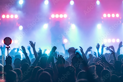 concert, silhouettes of happy people raising up hands, Music show. Bright scene lighting in club. Fans burn red flares at hip hop