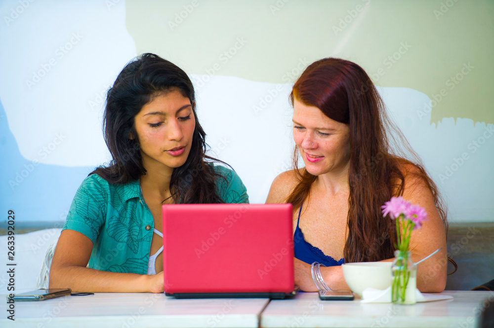 young happy caucasian woman and beautiful hispanic girl working at office cafe with laptop computer discussing as digital business partners and diversity ethnicity friends young happy caucasian woman and beautiful hispanic girl working at office cafe with laptop computer discussing as digital business partners and diversity ethnicity friends