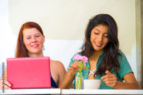 young happy and beautiful caucasian and latin women working at office cafe with laptop computer discussing as digital business partners and diversity ethnicity friends © TheVisualsYouNeed