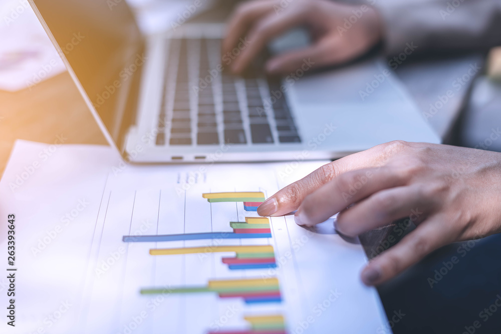 Business women point finger to the graph on paper and another hand type the data on labtop, working outside the office. Business women point finger to the graph on paper and another hand type the data on labtop, working outside the office.