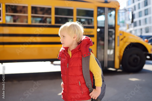 Pupil with schoolbag with yellow school bus on background.