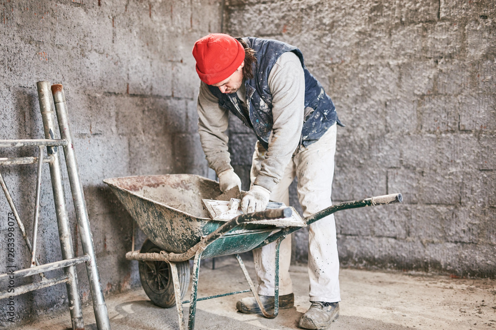 Real construction worker making a wall inside the new house. Real construction worker making a wall inside the new house.