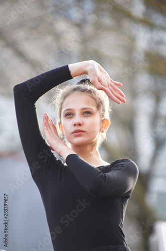 dancer posing in a city on a stairway in a black leotard.