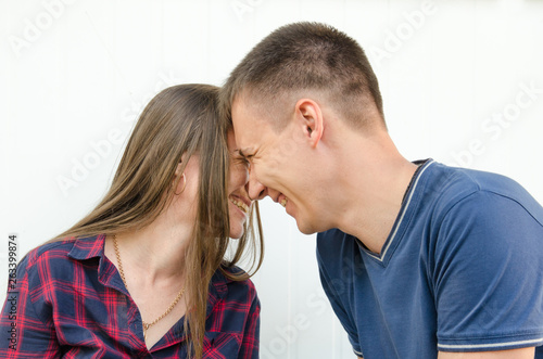 guy with short haircut and girl with long hair and freckles smiling touch their heads