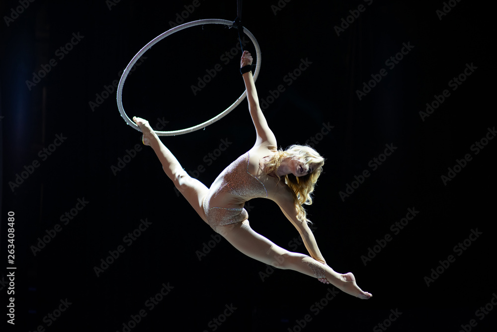 Obraz premium Graceful aerial acrobat doing her performance with a hoop isolated on black
