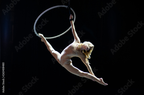 Graceful aerial acrobat doing her performance with a hoop isolated on black photo