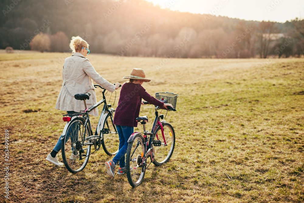 Fototapeta premium Mother and daughter with bicycles on countryside.