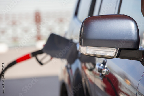 Fill the car with fuel. The car is filled with gasoline at a gas station. Gas station pump. Man refueling gasoline with fuel in a car, holding a nozzle. Limited depth of field. Blurred image