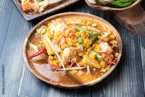 corn and papaya salad on wooden plate Thai style