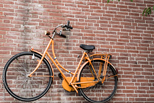 bike in Dutch national color orange, against brick wall background © Corinne