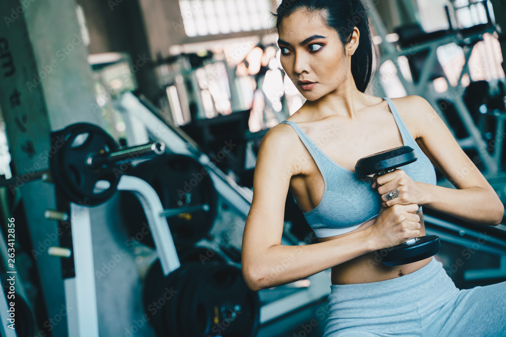 Wellbeing smart asian sport women lifting dumbbell in gym Wellbeing smart asian sport women lifting dumbbell in gym