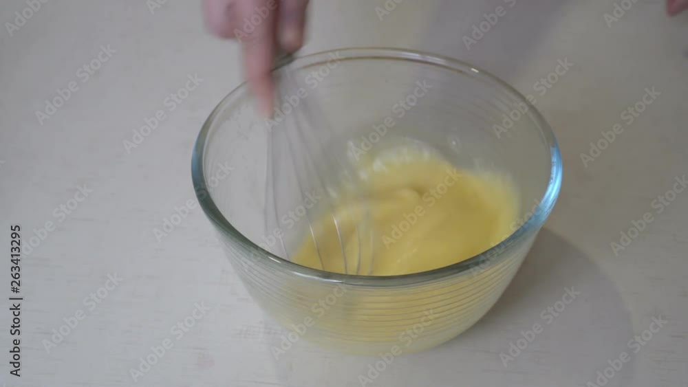 A woman whips eggs with a whisk in a glass bowl on a white table for cooking. Close up. The view from the top. 4K. 25 fps A woman whips eggs with a whisk in a glass bowl on a white table for cooking. Close up. The view from the top. 4K. 25 fps