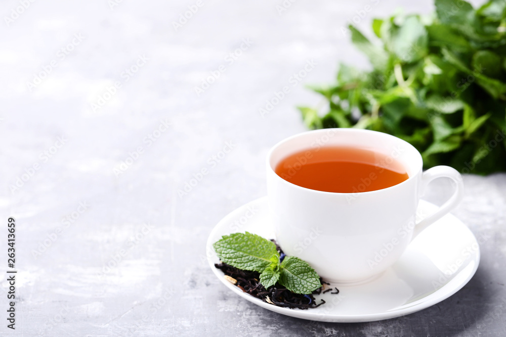 Cup of tea with mint leafs on grey wooden table Cup of tea with mint leafs on grey wooden table