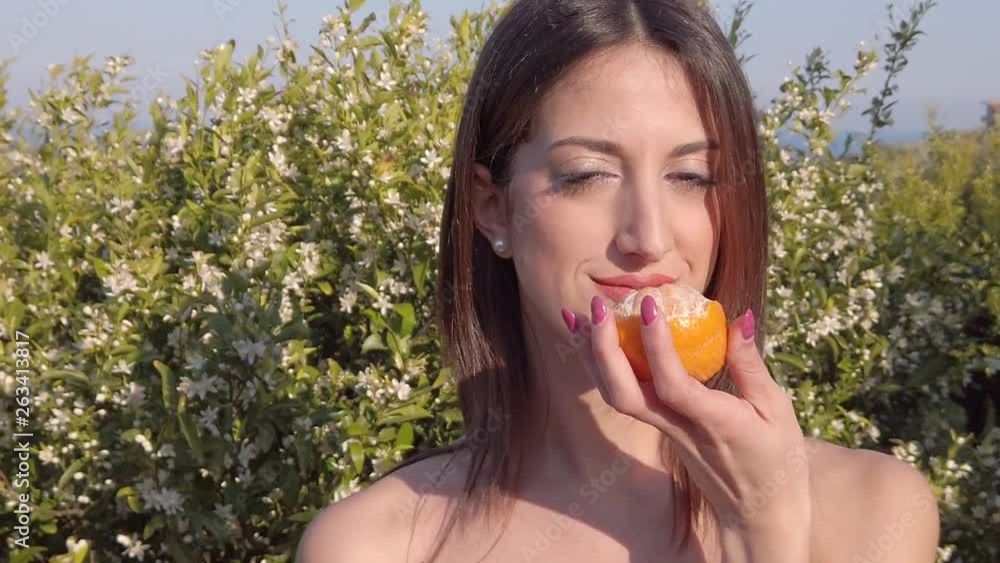 Bellissima ragazza contadina raccoglie un' arancia e un mandarino dall'albero, in campagna e lo annusa. Bellissima ragazza contadina raccoglie un' arancia e un mandarino dall'albero, in campagna e lo annusa.