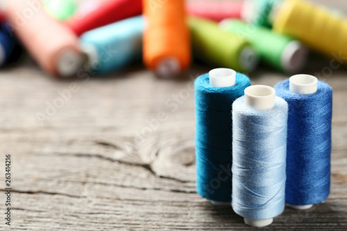 Colourful thread spools on grey wooden table