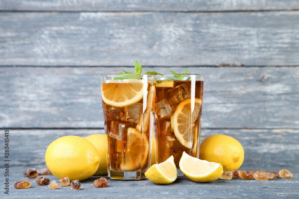 Ice tea in glasses with lemon and mint leafs on wooden table Ice tea in glasses with lemon and mint leafs on wooden table