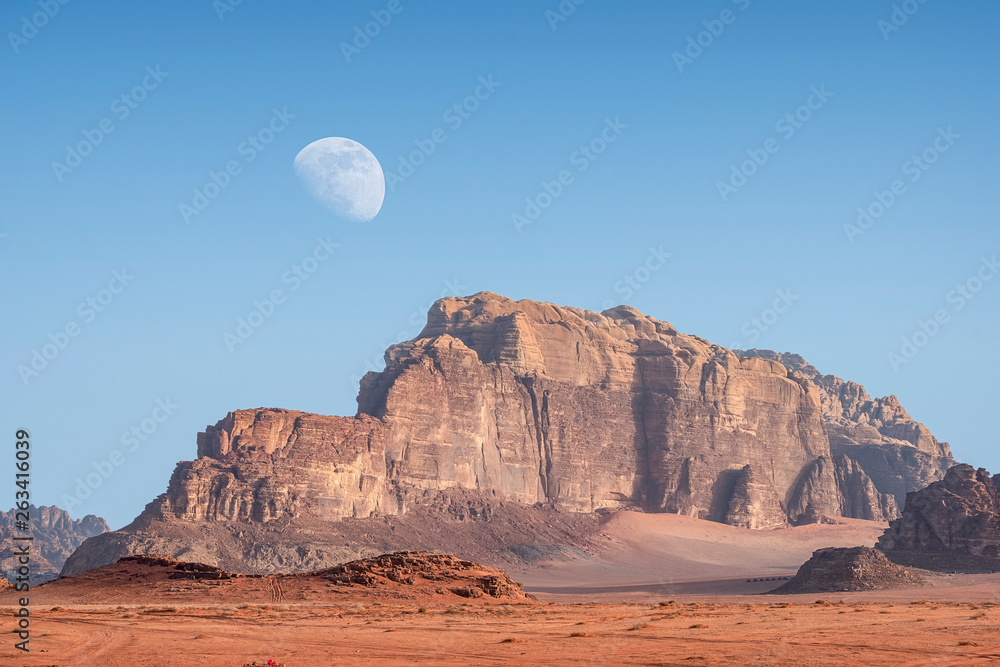  incredible lunar landscape with huge moon in Wadi Rum village in the Jordanian red sand desert. Wadi Rum also known as The Valley of the Moon,  Jordan - Image