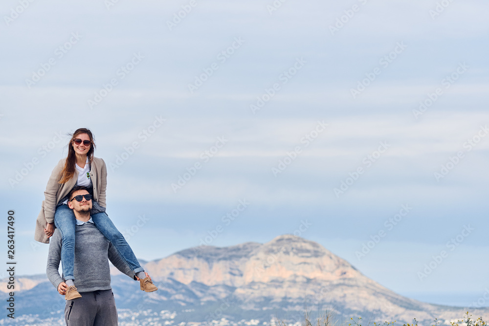 Young cute girl sitting on shoulders of her boyfriend