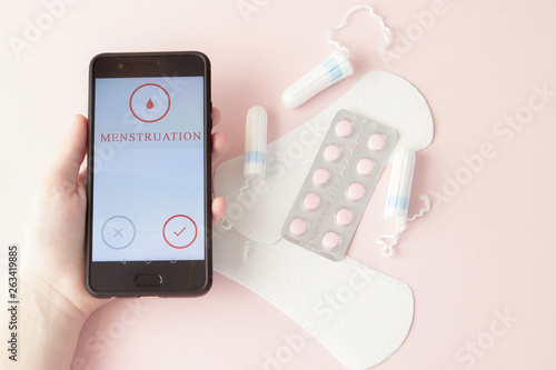 Tampon, feminine, sanitary pads for critical days, feminine calendar, pain pills during menstruation on a pink background. Tracking the menstrual cycle and ovulation