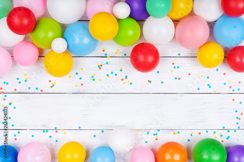 Heap of colorful balloons and confetti on white table top view. Festive or party background. Flat lay. Birthday greeting card.