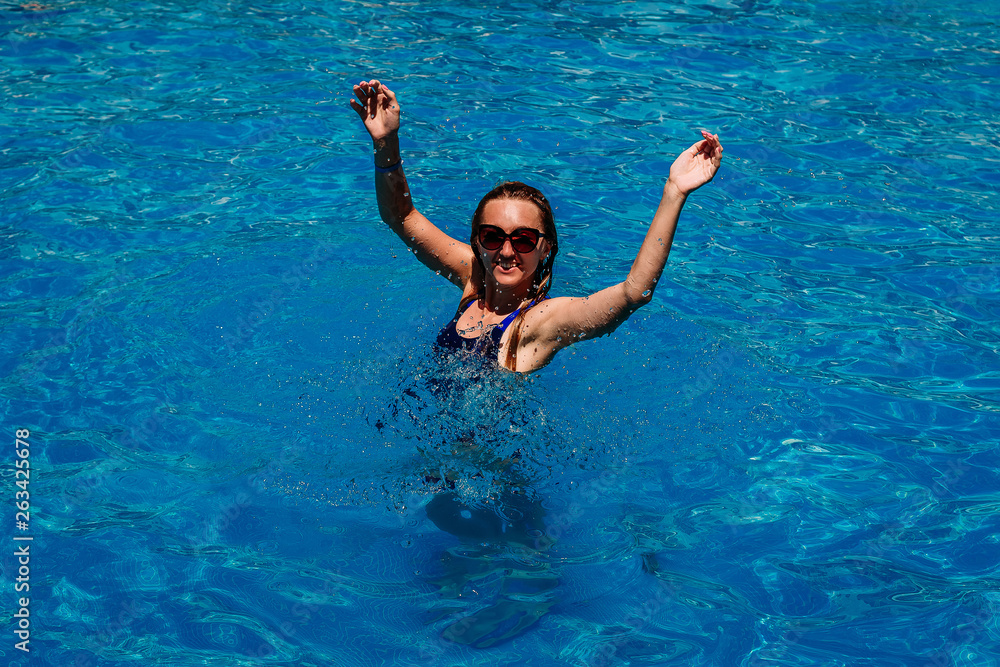 smiling young happy woman in blue water pool.