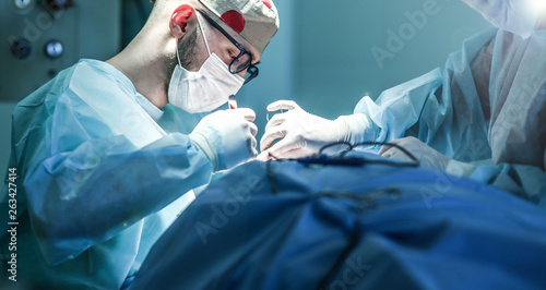 Young male plastic surgeon operates in the operating room of a medical center. photo