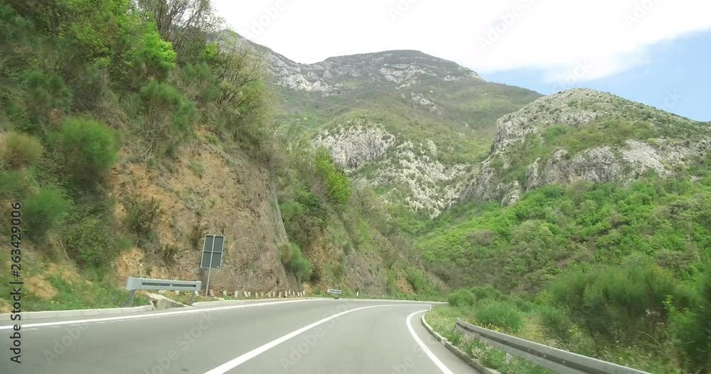 Beautiful view from the window of moving car. Frontal view through the windshield during the car drive on a sunny spring day. Picturesque country roads of southern Montenegro, winding mountain serpent Beautiful view from the window of moving car. Frontal view through the windshield during the car drive on a sunny spring day. Picturesque country roads of southern Montenegro, winding mountain serpent