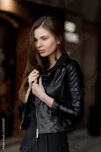 The girl in the black leather jacket on the street. Beauty in the big city.